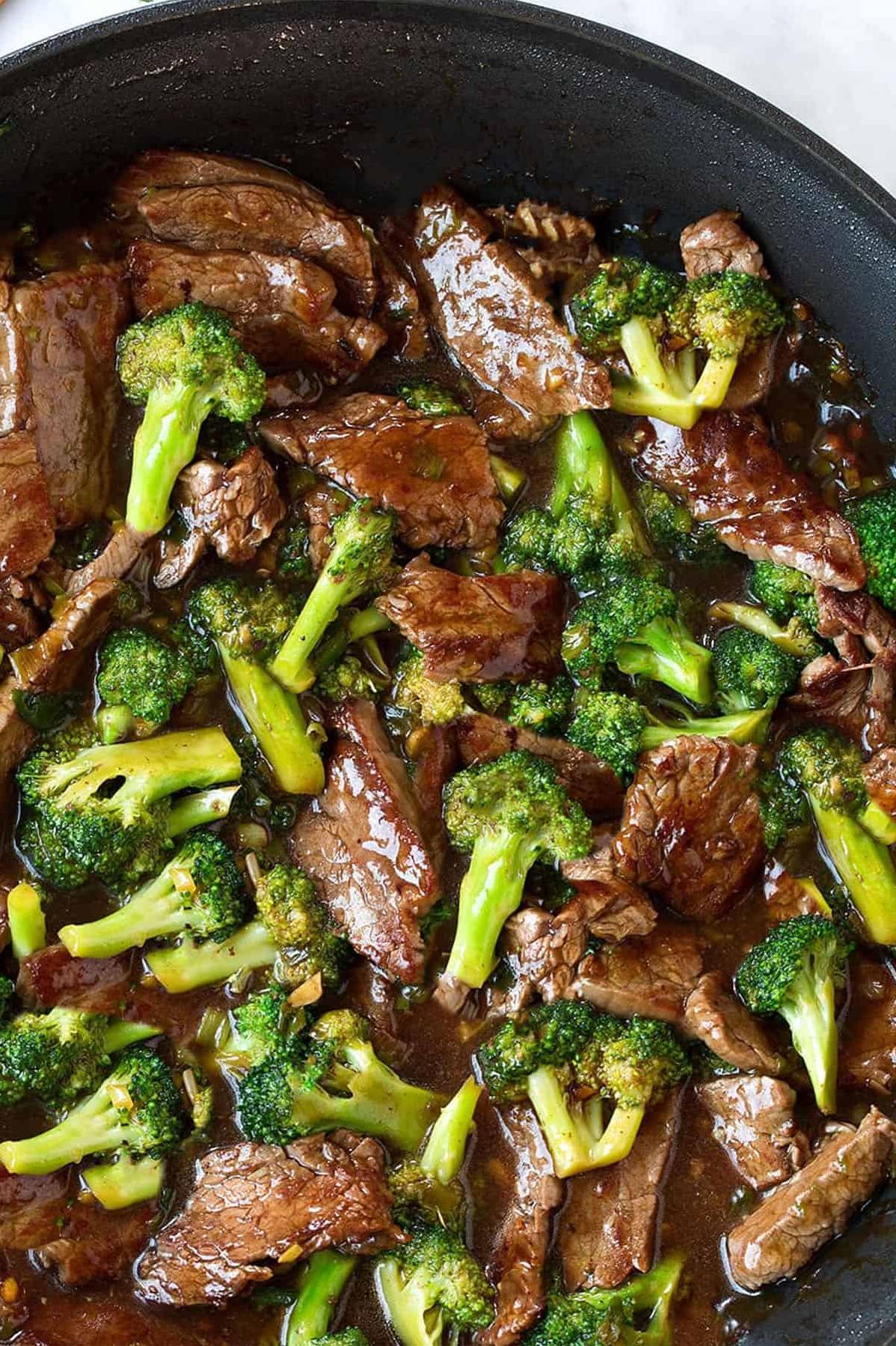  A plate of perfectly seared beef strips alongside fresh broccoli and a flavorful wine sauce.