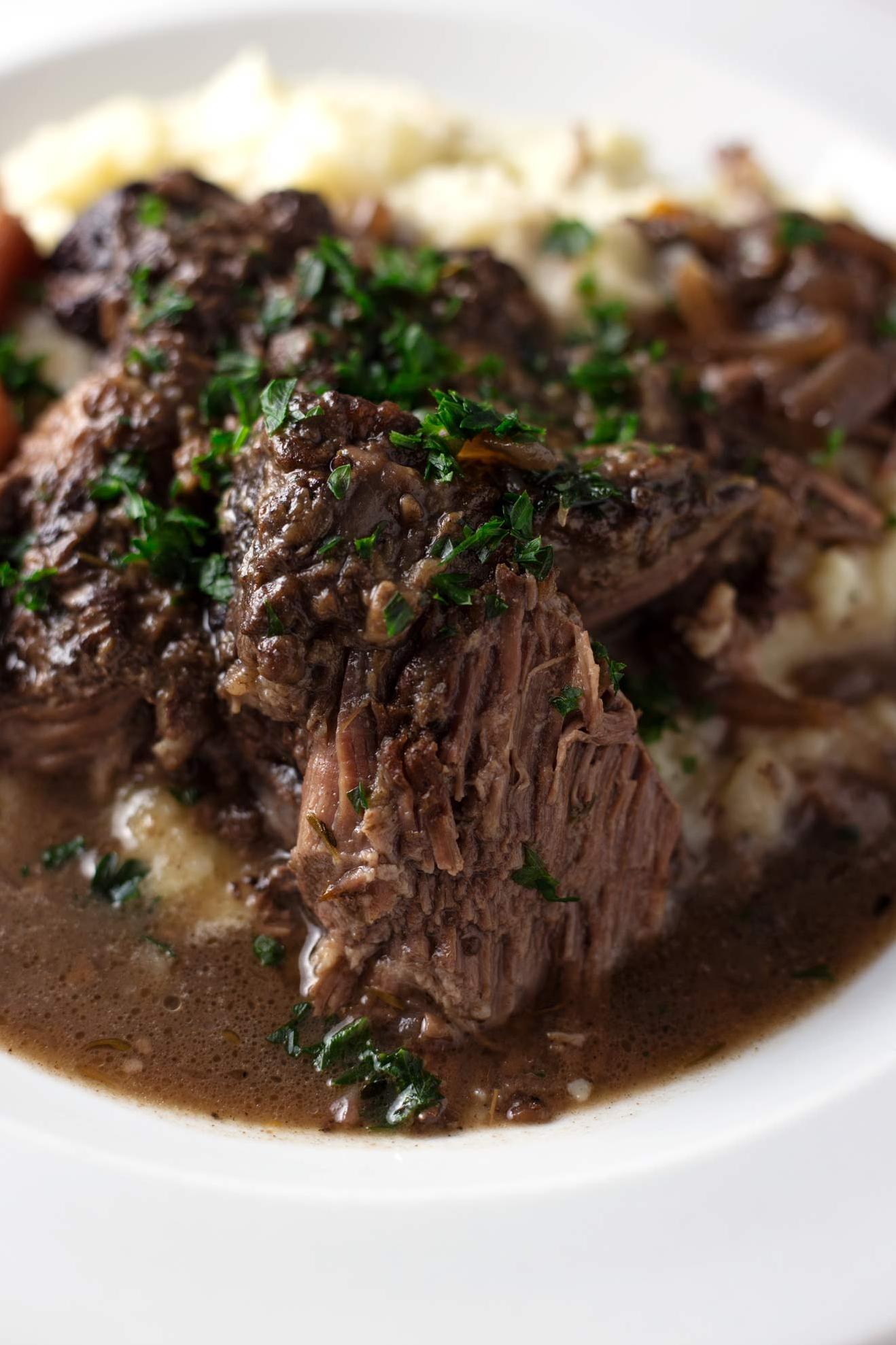  The savory aroma of garlic fills the air as the pot roast slowly simmers in a flavorful bath of red wine.